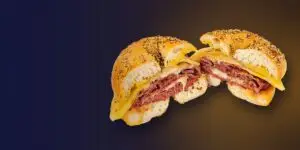 Hot corned beef and melted Swiss on a toasted everything bagel with mustard, cut in half